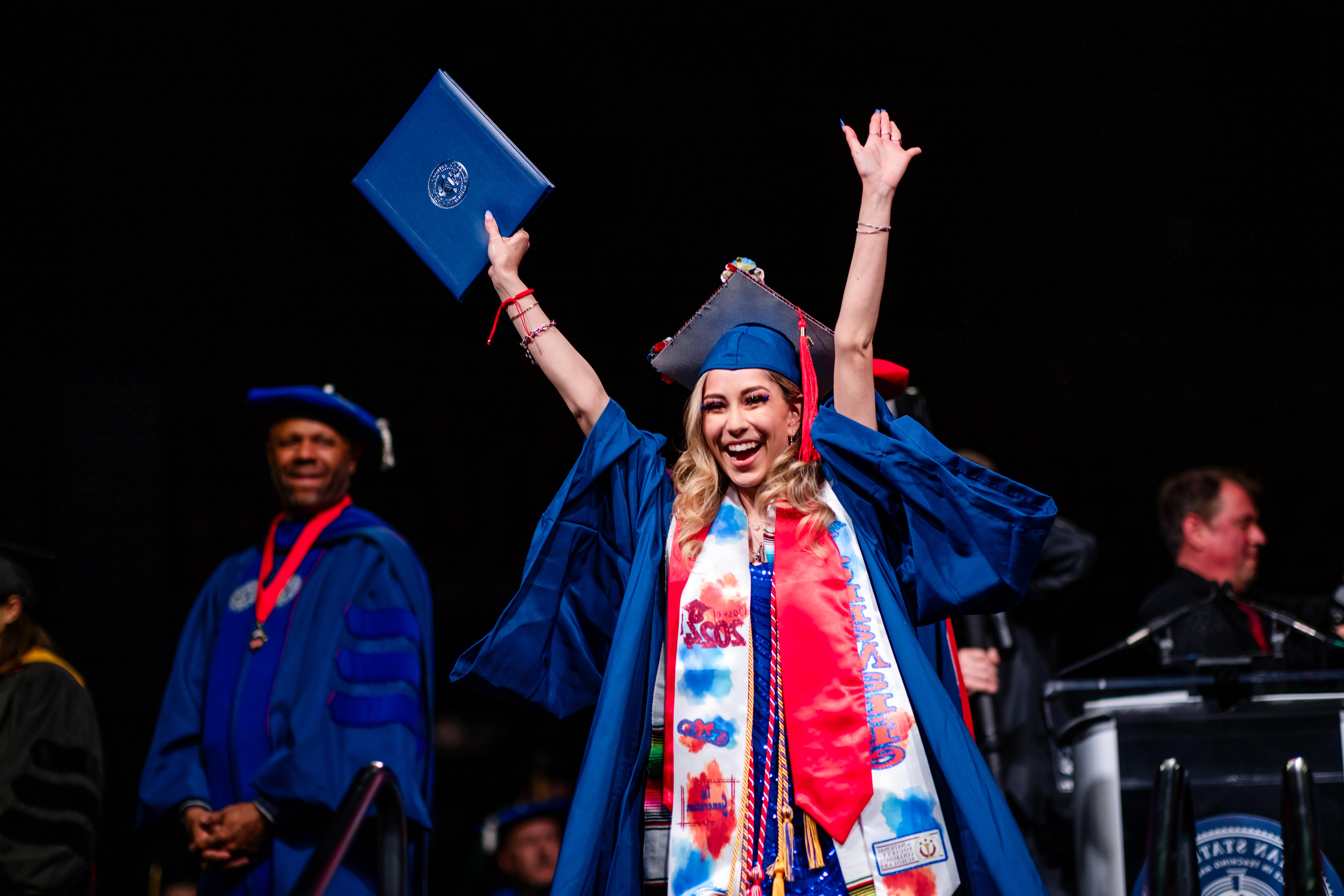 毕业典礼上，一名毕业生从讲台上走下来，举起双手庆祝